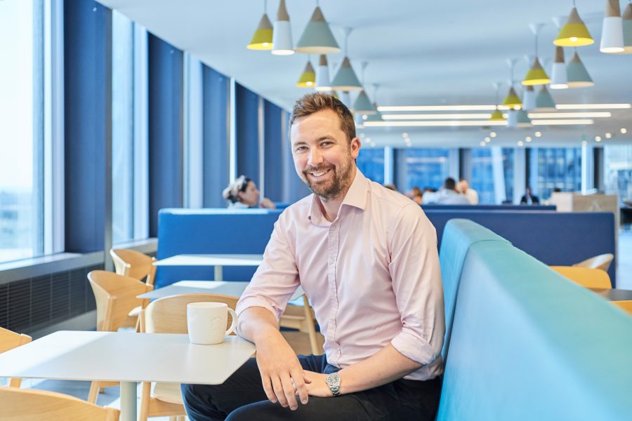 Man sat in the canteen at St Helen's, London smiling to camera