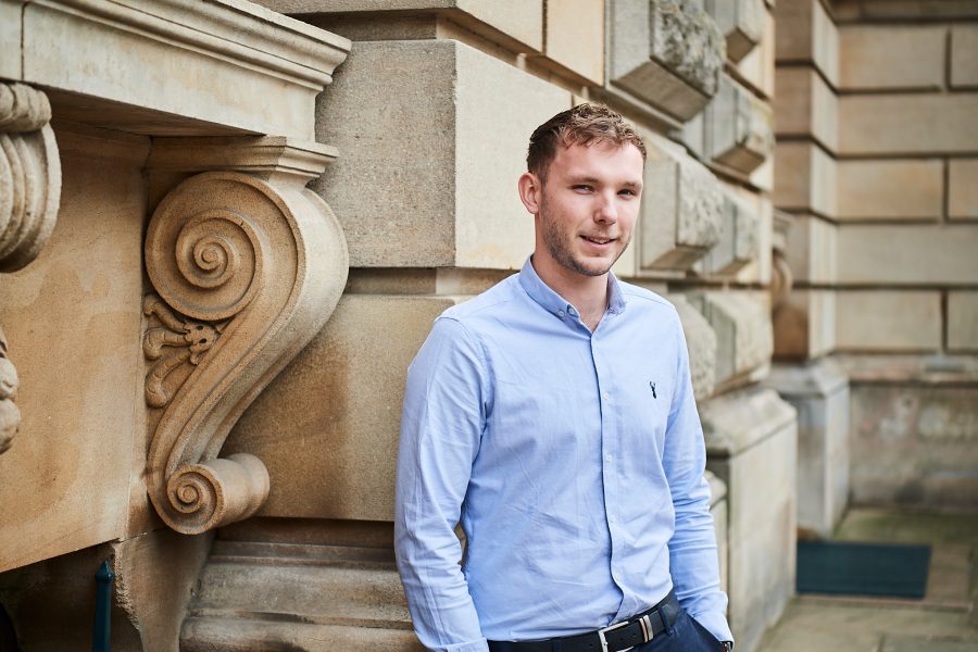 Man smiling towards the camera outside a building