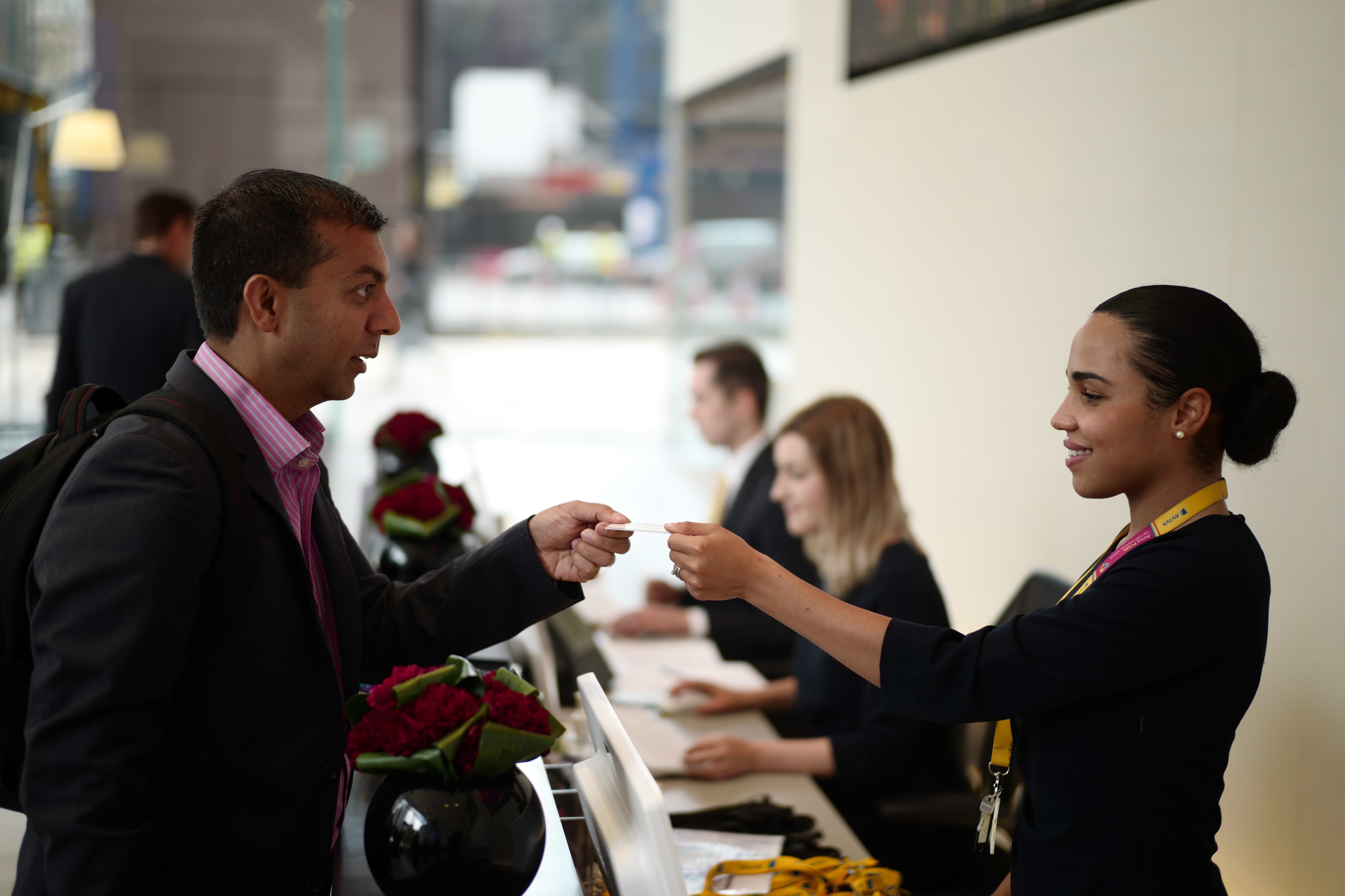 Man receiving guest pass from woman behind counter at Aviva London headquarters